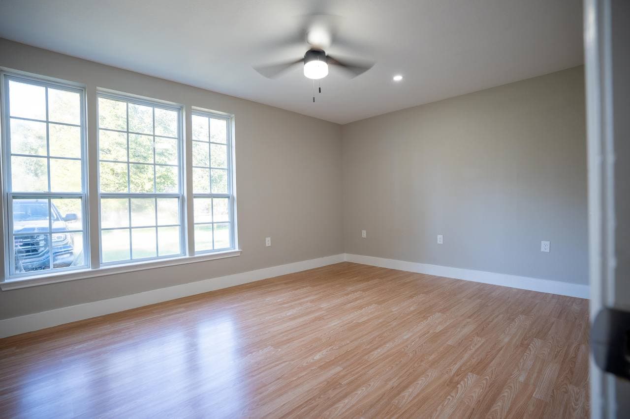 Master bedroom with triple windows and new hardwood flooring