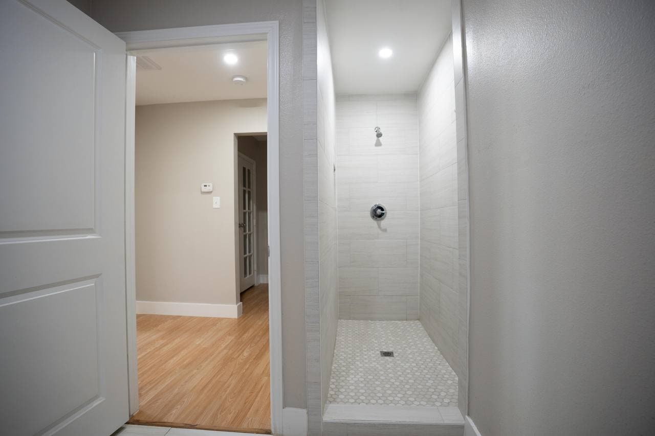 Walk-in tile shower with mosaic floor and recessed lighting