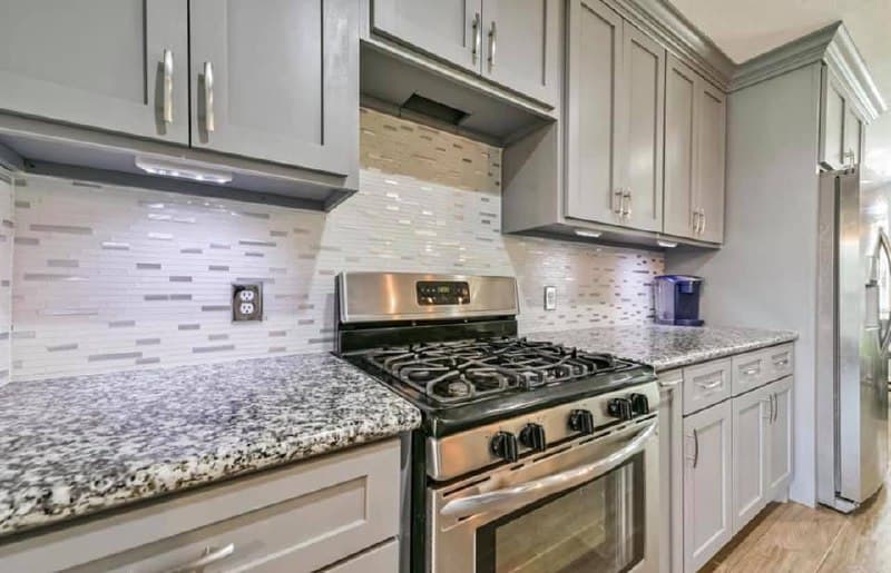 Kitchen renovation backsplash detail with gray cabinets and granite countertops