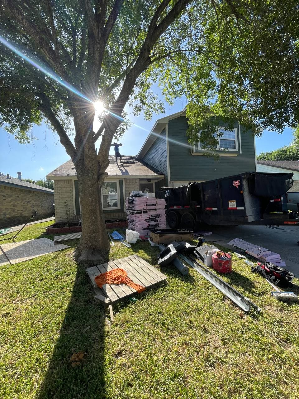 Roofing crew at work, shingles staged in driveway